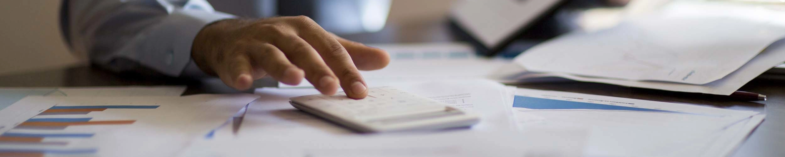 Man using calculator while reviewing charts.