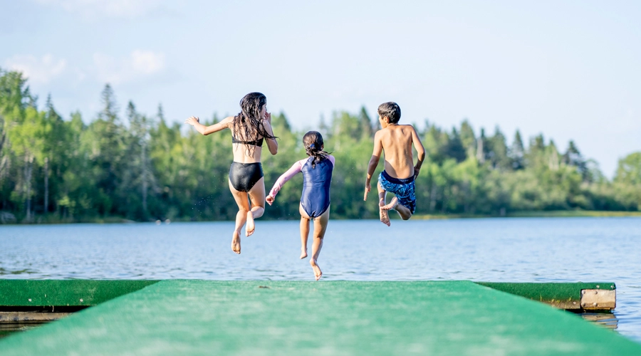 Children jumping off a dock into water.